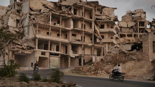 Motorräder fahren an Gebäuden vorbei, die im Zuge der Kämpfe in der Provinz Idlib zerstört wurden. Motorräder fahren an Gebäuden vorbei, die im Zuge der Kämpfe in der Provinz Idlib zerstört wurden.