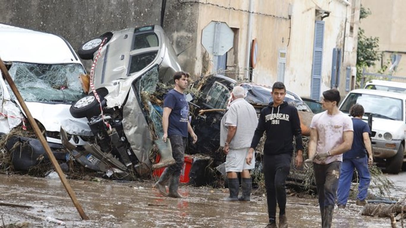 Einwohner von Sant Llorenc des Cardassar gehen nach dem schweren Unwetter an Autowracks vorbei.