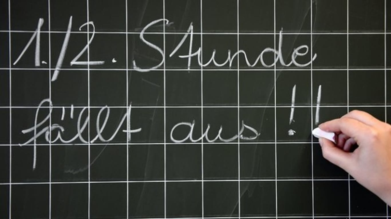 Eine Lehrerin schreibt in einer Grundschule an die Tafel: An Deutschlands Schulen fehlen innerhalb von zehn Jahren nach offizieller Prognose 18.000 Lehrer.