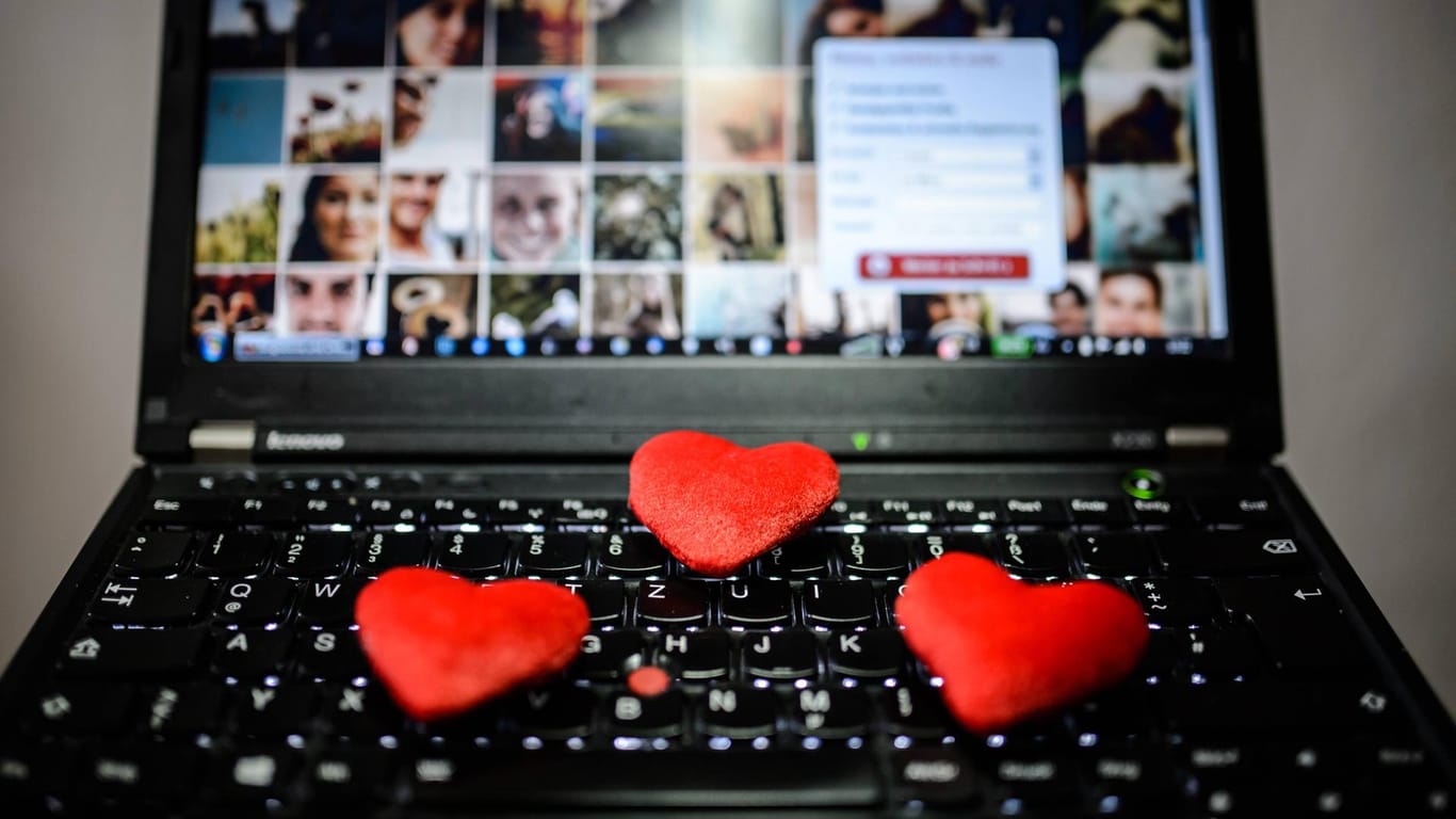 Deko-Herzchen liegen auf einer Laptop-Tastatur: Auf vielen Dating-Portalen tummeln sich auch Betrüger.