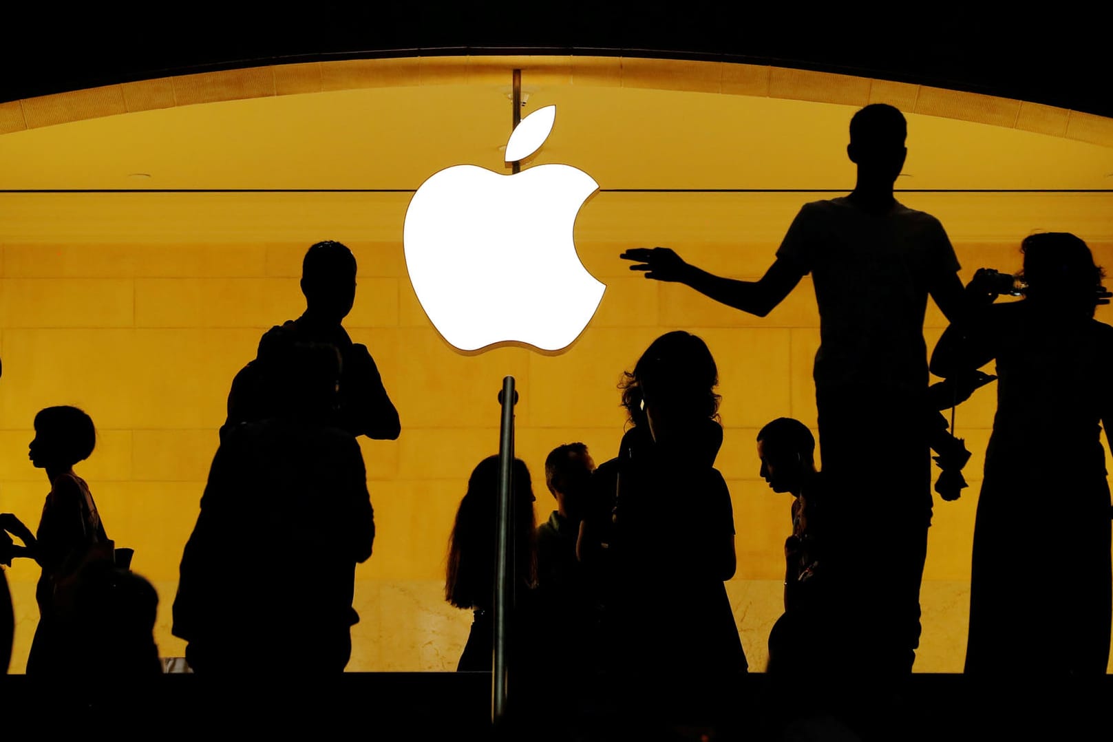 Menschliche Silhouetten vor dem Apple-Logo: Der iPhone-Konzern hat im Patentstreit mit dem Chip-Hersteller Qualcomm einen Teilsieg errungen.