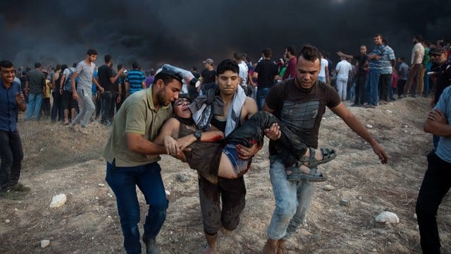 Palästinenser tragen einen verwundeten Jugendlichen, der während Zusammenstößen mit israelischen Truppen angeschossen wurde. Palästinenser tragen einen verwundeten Jugendlichen, der während Zusammenstößen mit israelischen Truppen angeschossen wurde.