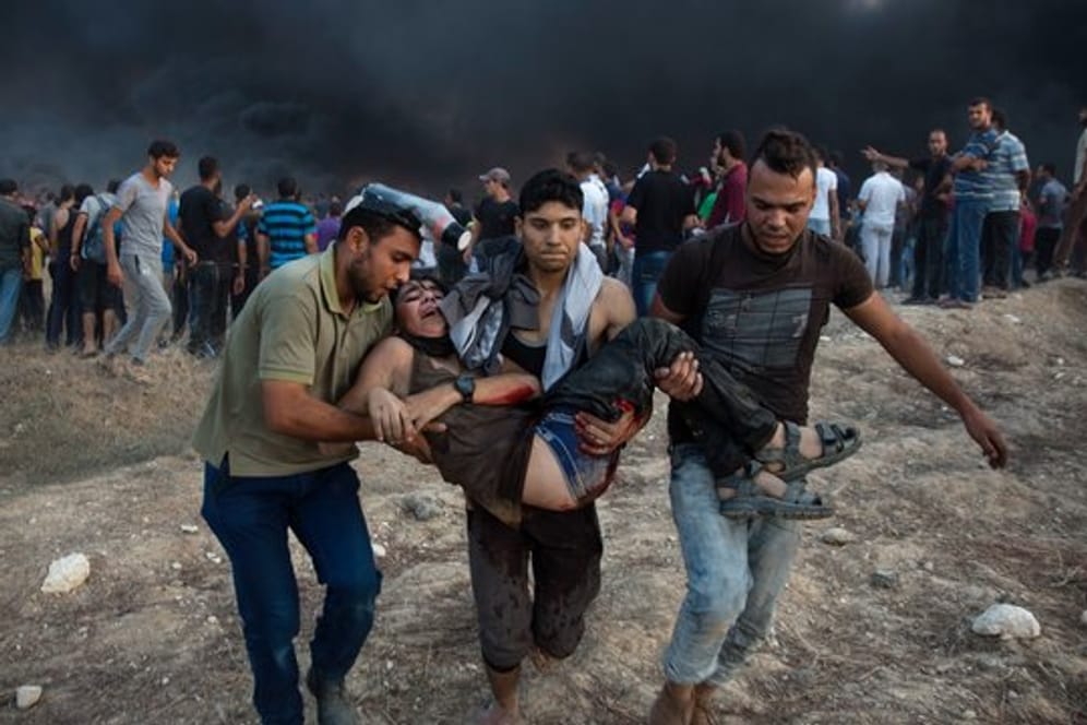 Palästinenser tragen einen verwundeten Jugendlichen, der während Zusammenstößen mit israelischen Truppen angeschossen wurde.