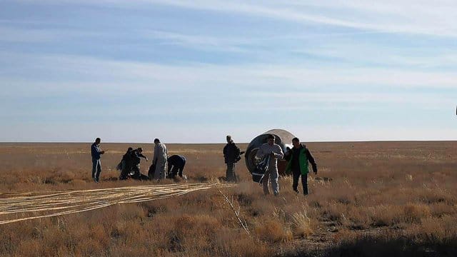 Rettungsmannschaften stehen neben der notgelandeten russischen Sojus-Kapsel in der Steppe von Kasachstan. Rettungsmannschaften stehen neben der notgelandeten russischen Sojus-Kapsel in der Steppe von Kasachstan.