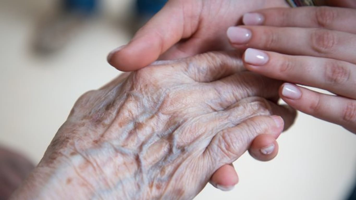 Eine Pflegerin hält die Hand einer älteren Dame.
