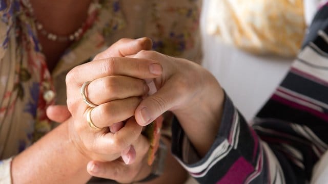 Eine Therapeutin hält in einem Hospiz in Stuttgart die Hand einer todkranken Bewohnerin. Eine Therapeutin hält in einem Hospiz in Stuttgart die Hand einer todkranken Bewohnerin.