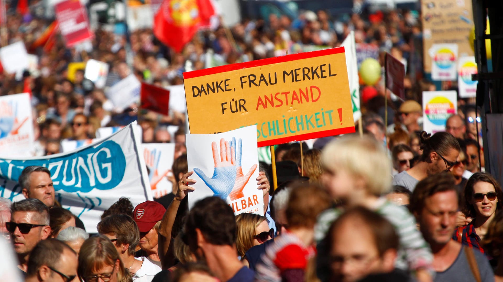 Auf den Schildern und Transparenten bei der "Unteilbar"-Demo bekommt auch die Kanzlerin gelegentlich positives Feedback.