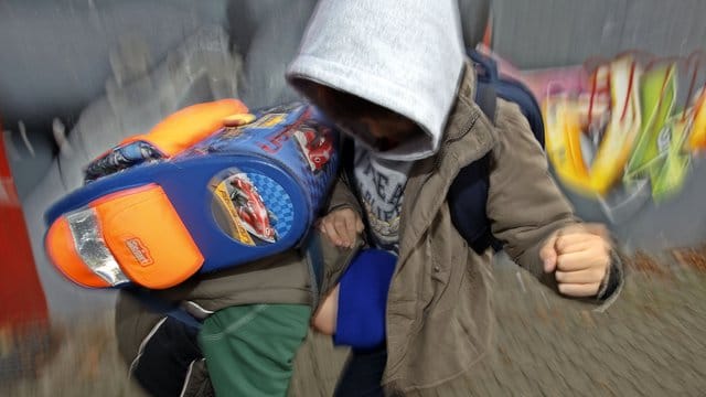 Zwei Schüler schlagen sich auf einem Schulhof.