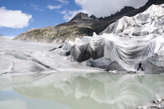 Arbeiter befestigen weiße Spezialdecken am Rhonegletscher, um den ältesten Gletscher der Alpen vor dem Schmelzen zu bewahren.