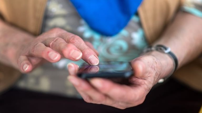 Eine Seniorin tippt auf ihrem Smartphone