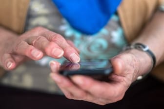 Eine Seniorin tippt auf ihrem Smartphone