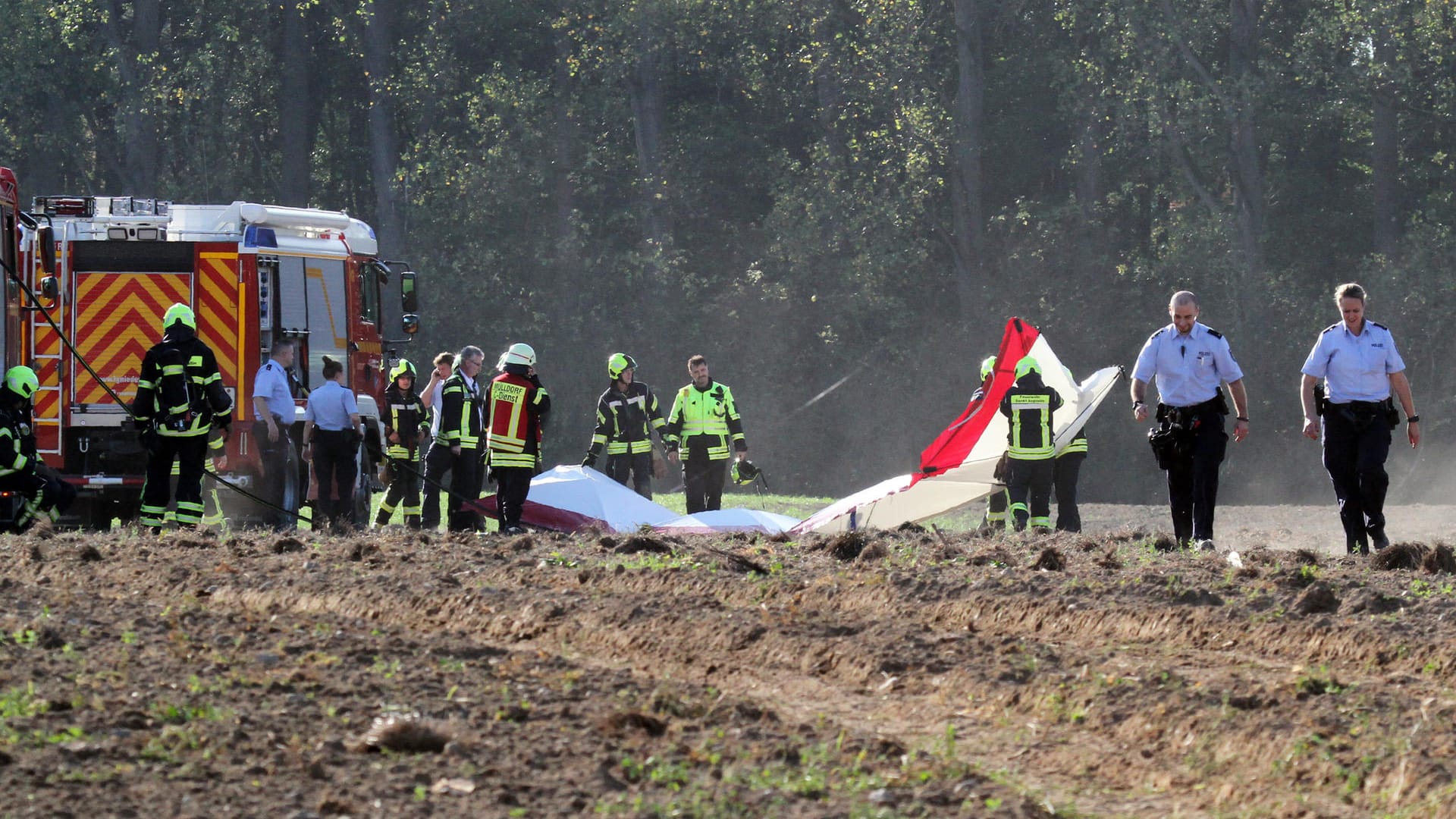 Auf einem Feld untersuchen Rettungskräfte die Trümmer des Kleinflugzeugs: Mit einem Großaufgebot war die Feuerwehr im Einsatz. Auf einem Feld untersuchen Rettungskräfte die Trümmer des Kleinflugzeugs: Mit einem Großaufgebot war die Feuerwehr im Einsatz.