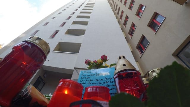 Von irgendwo da oben kam der Holzklotz: Blumen, Kerzen und Karten vor einem Hochhaus im Märkischen Viertel, wo ein acht Jahre alter Junge starb.