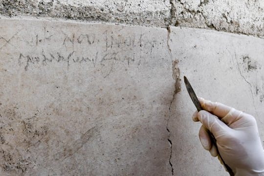 Ein Archäologe zeigt an einer Mauer in Pompeji die Kohle-Inschrift, die auf die Eruption des Vesuv im Jahr 79 verweist.