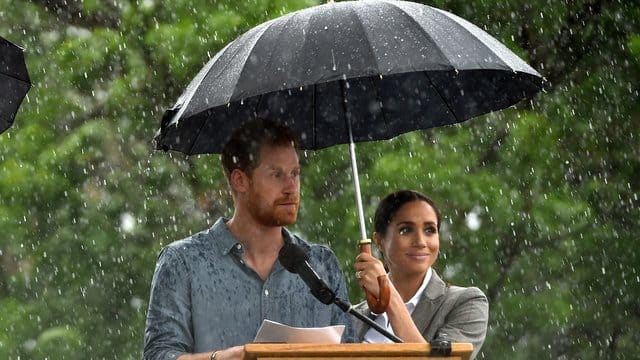 Prinz Harry neben Herzogin Meghan, die während eines Regenschauers einen Schirm hält, in Gubbo. Prinz Harry neben Herzogin Meghan, die während eines Regenschauers einen Schirm hält, in Gubbo.