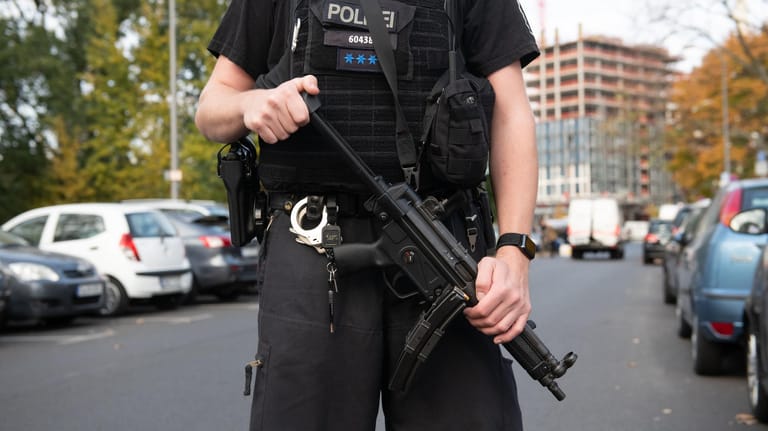 Schwer bewaffneter Polizist am Tatort: Im Hintegrund ist der aufgebrochene Geldtransporter zu sehen.