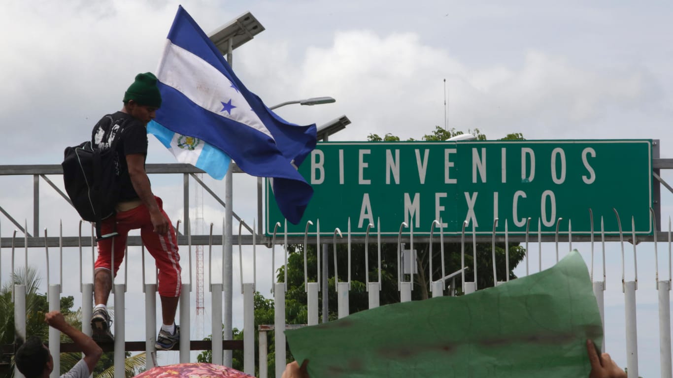 "Willkommen in Mexiko": Ein junger Mann ist mit der Flagge von Honduras auf den Grenzzaun zwischen Guatemala und Mexiko geklettert.
