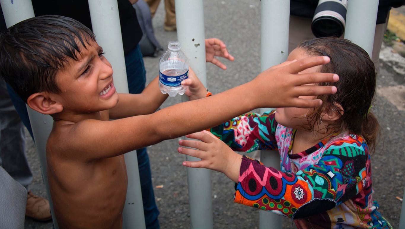 Zwei Kinder, die zu einer Gruppe honduranischer Migranten gehören, warten auf einer Brücke, die Guatemala und Mexiko verbindet: Unter den Migranten sind viele Kinder und Frauen.