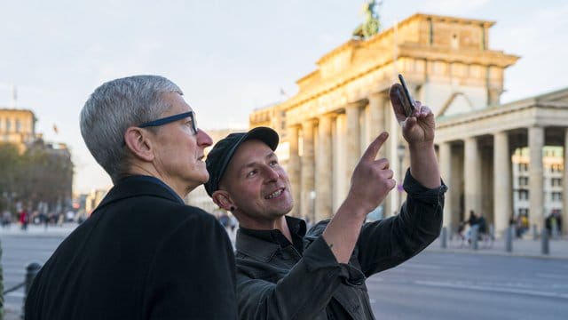 Apple-Chef Tim Cook (l) lässt sich am Brandenburger Tor von Entwickler Peter Kolski das Projekt "MauAR" erklären.