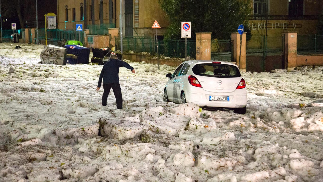 Ein Mann versucht, ein durch Hagelmassen blockiertes Auto zu erreichen: Besonders im östlichen Teil von Rom kam viel Hagel herunter.
