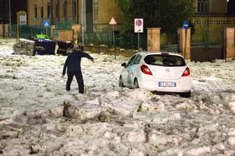 Ein Mann versucht, ein durch Hagelmassen blockiertes Auto zu erreichen: Besonders im östlichen Teil von Rom kam viel Hagel herunter.