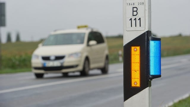 Ein Wildwarnreflektor leuchtet an einem Leitpfosten an der B111 bei Wolgast in Mecklenburg-Vorpommern.