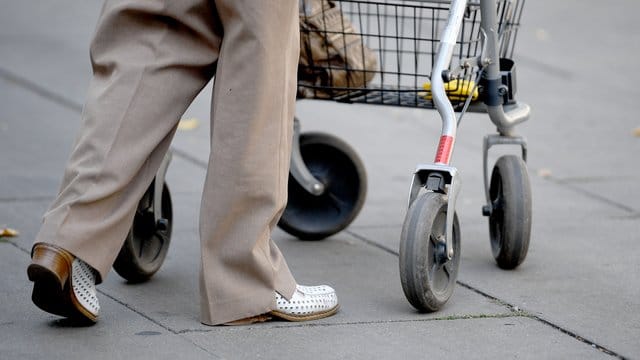 Eine Rentnerin geht mit Hilfe eines Rollators