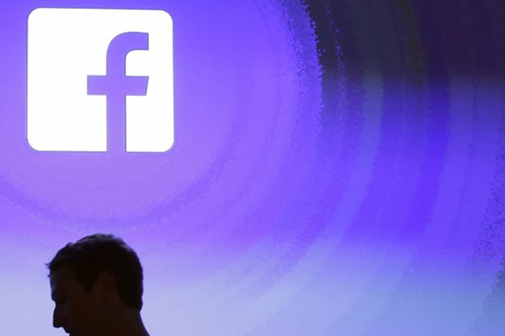 Der Schatten des Chefs: Mark Zuckerberg geht am Firmensitz an einem leuchtenden Facebooklogo vorbei.