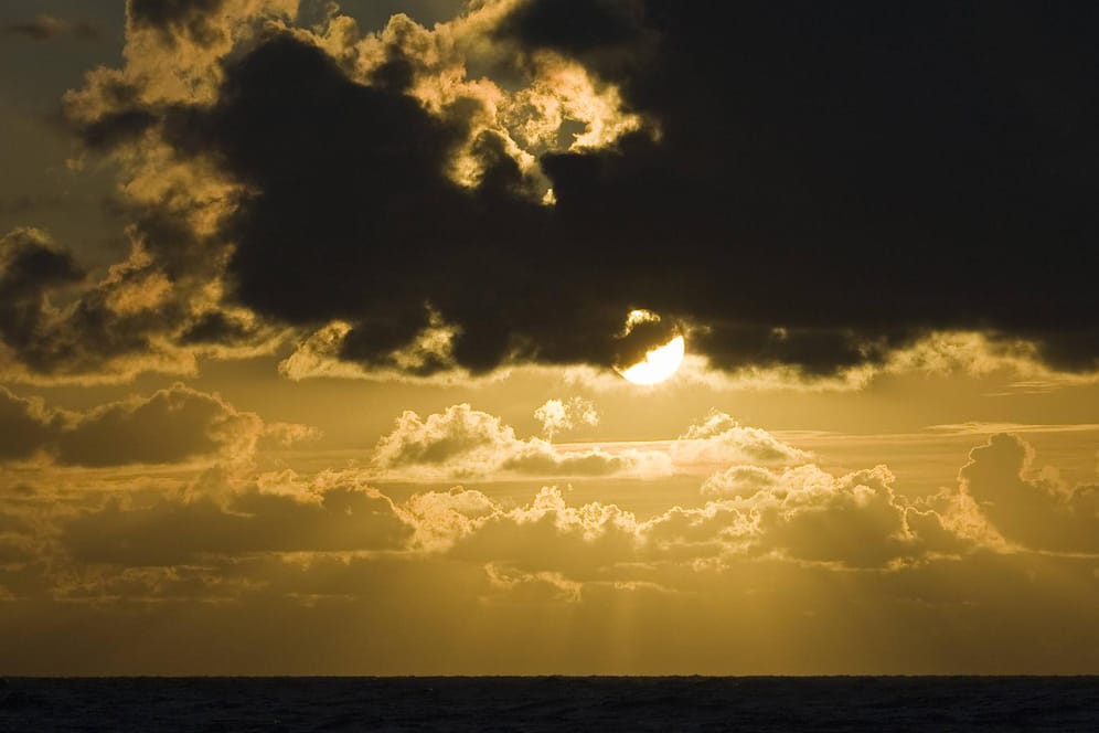 Dunkle Wolken über der Nordsee bei Sonnenuntergang: Nach schlechten Wetter am Wochenende wird es in der nächsten Woche wieder deutlich freundlicher.