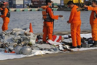 Mitarbeiter der Indonesischen Such- und Rettungsbehörde inspizieren Trümmerteile.