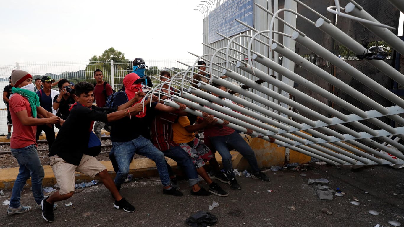 Eine Gruppe von Männern reißt den Zaun an der guatemaltekischen Grenze nieder: Die Migranten wollen in die USA einreisen.