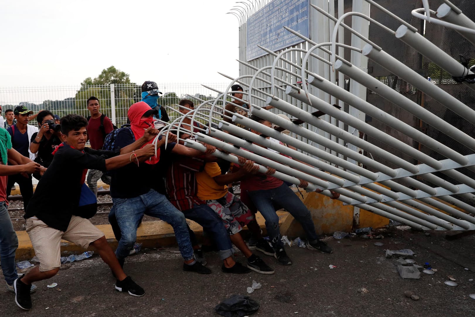 Eine Gruppe von Männern reißt den Zaun an der guatemaltekischen Grenze nieder: Die Migranten wollen in die USA einreisen.