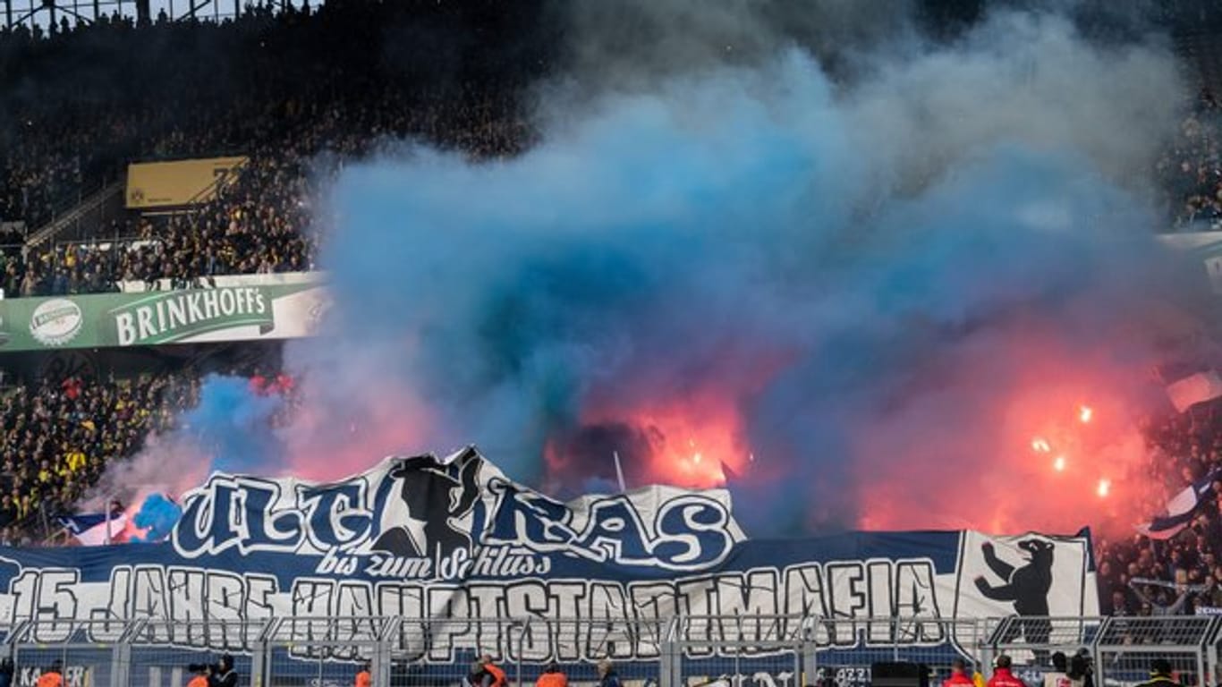 Hinter ihrem Banner brennen Fans von Hertha BSC exzessiv Feuerwerkskörper ab, was ein Einschreiten der Polizei bewirkt.