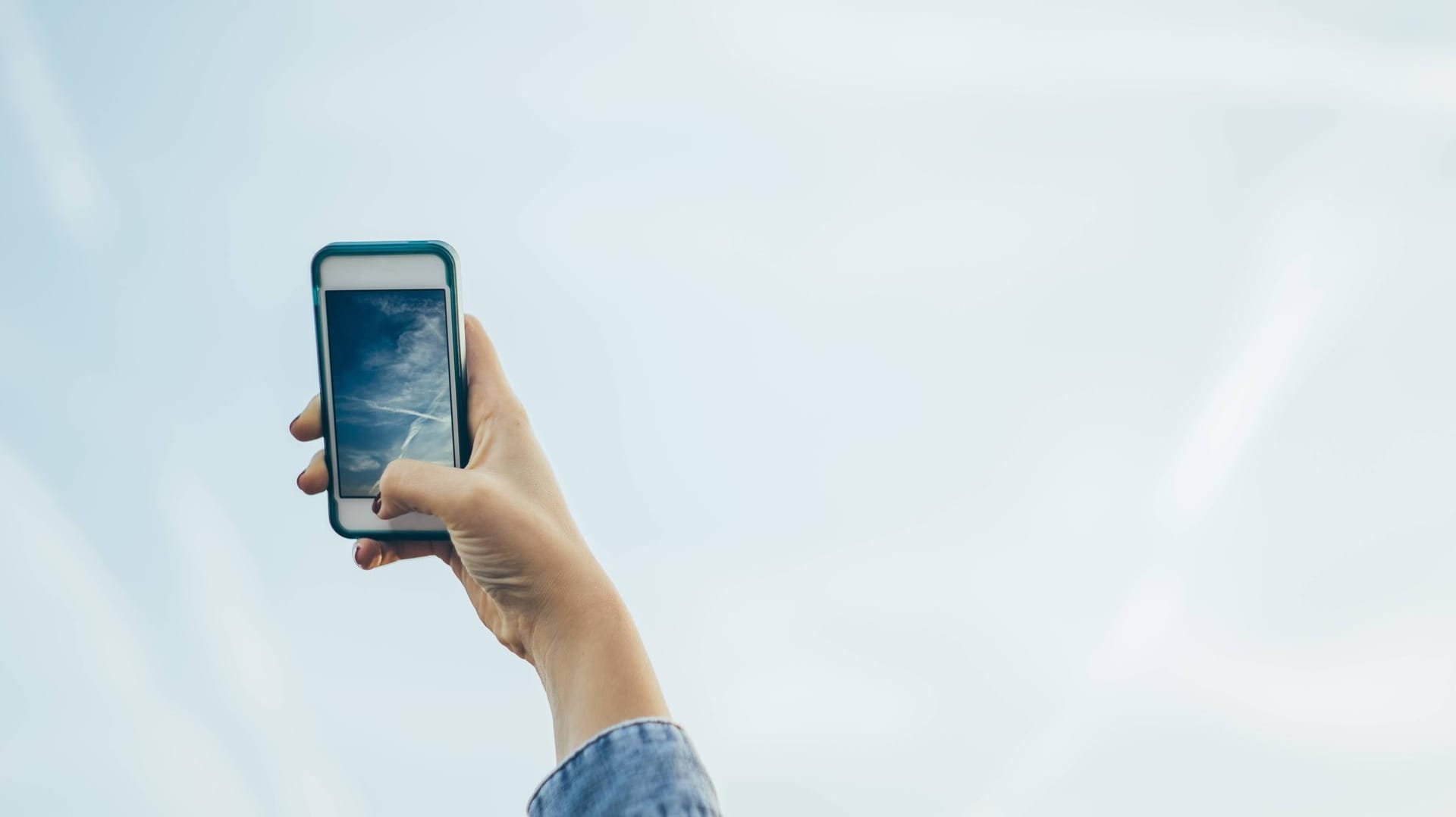 Ein Nutzer richtet die iPhone-Kamera auf den blauen Himmel: Die Wetter-App unter iOS 12 warnt seit einiger Zeit an vielen Orten vor schlechter Luftqualität - scheinbar grundlos.