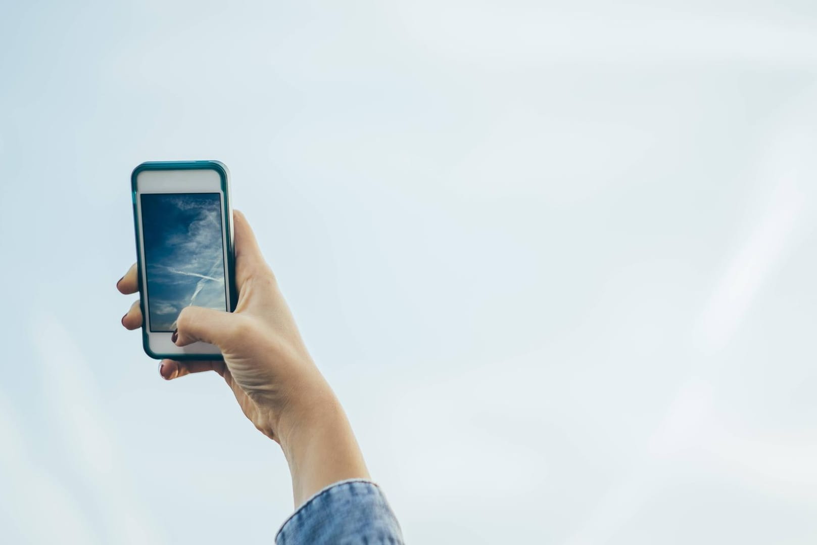 Ein Nutzer richtet die iPhone-Kamera auf den blauen Himmel: Die Wetter-App unter iOS 12 warnt seit einiger Zeit an vielen Orten vor schlechter Luftqualität - scheinbar grundlos.