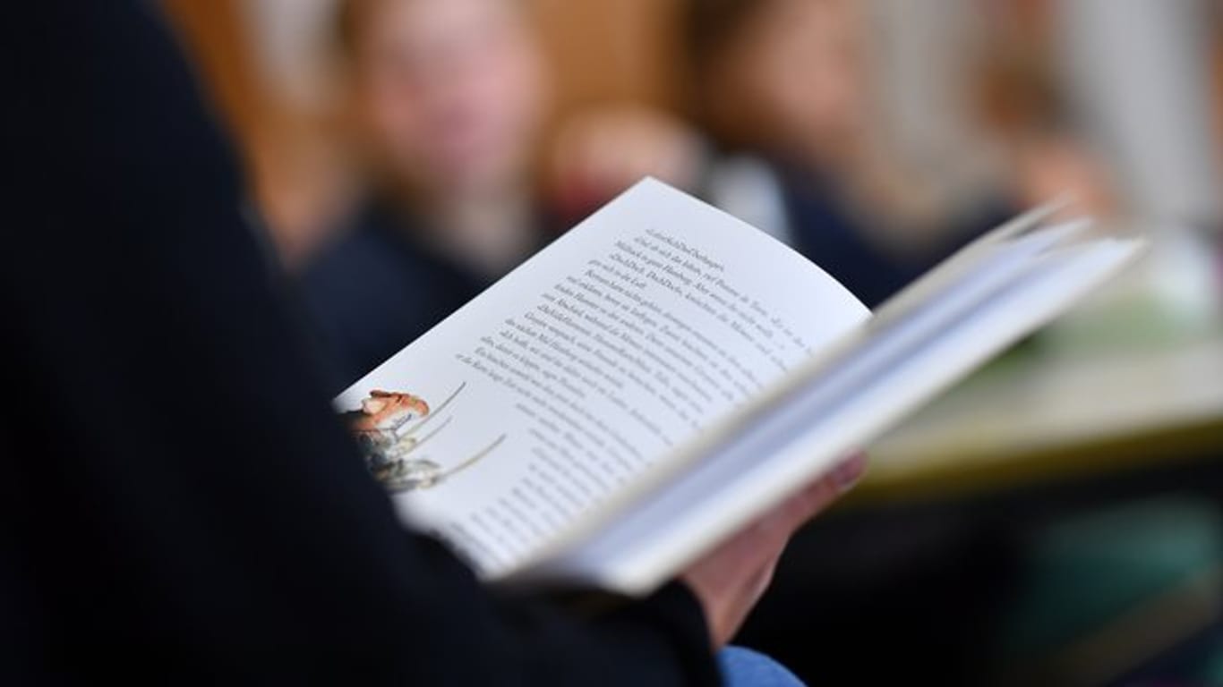 Eine Lehrerin liest in einer Grundschule in ihren Drittklässlern aus einem Buch vor.