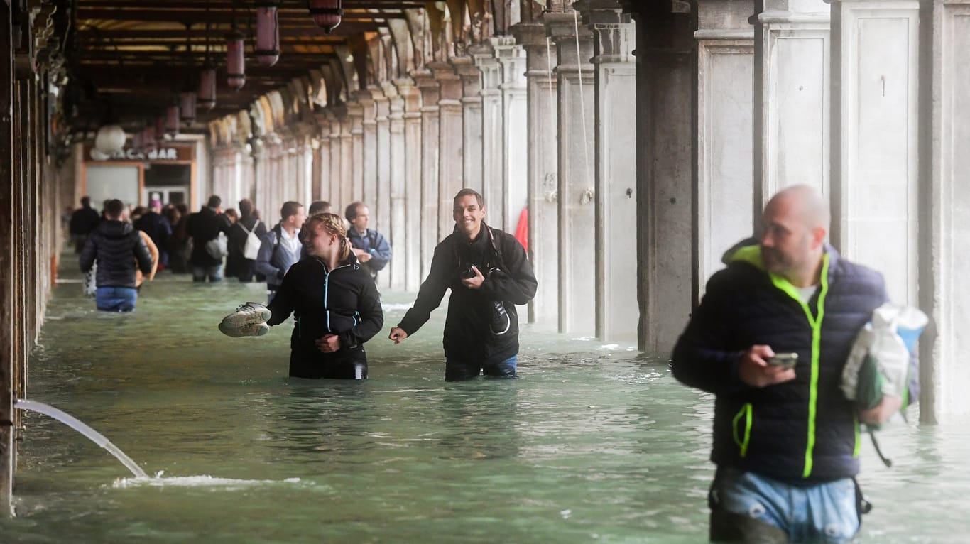 Touristen bahnen sich in Venedig unter Arkaden am überfluteten Markusplatz ihren Weg: Die Stadt trifft das schlimmste Hochwasser seit Jahren.