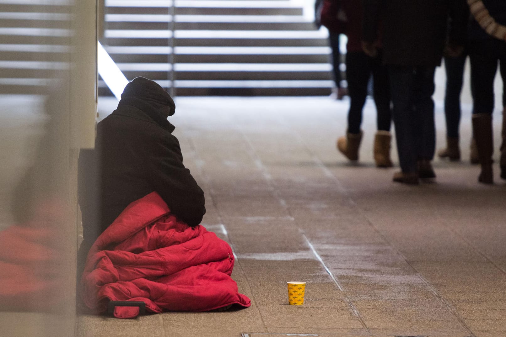 Ein Bettler sitzt in einer Unterführung während Passanten vorbeilaufen: Jeder fünfte Deutsche ist von Armut oder sozialer Ausgrenzung bedroht. Bei der letzten Erhebung waren die Zahlen noch höher.