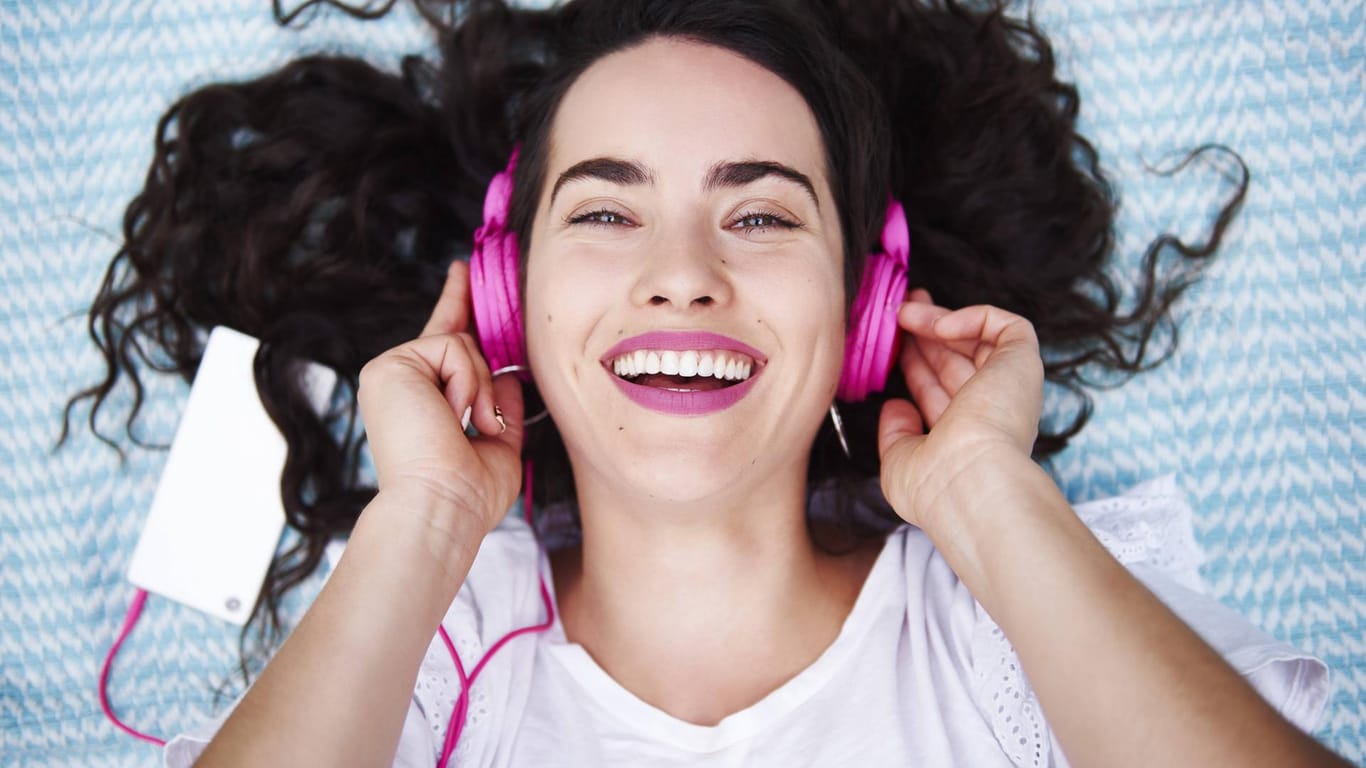 Eine junge Frau hört über pinke Kopfhörer Musik: Sogenannte "Zero Rating"-Tarife sind vor allem bei jungen Nutzern beliebt.