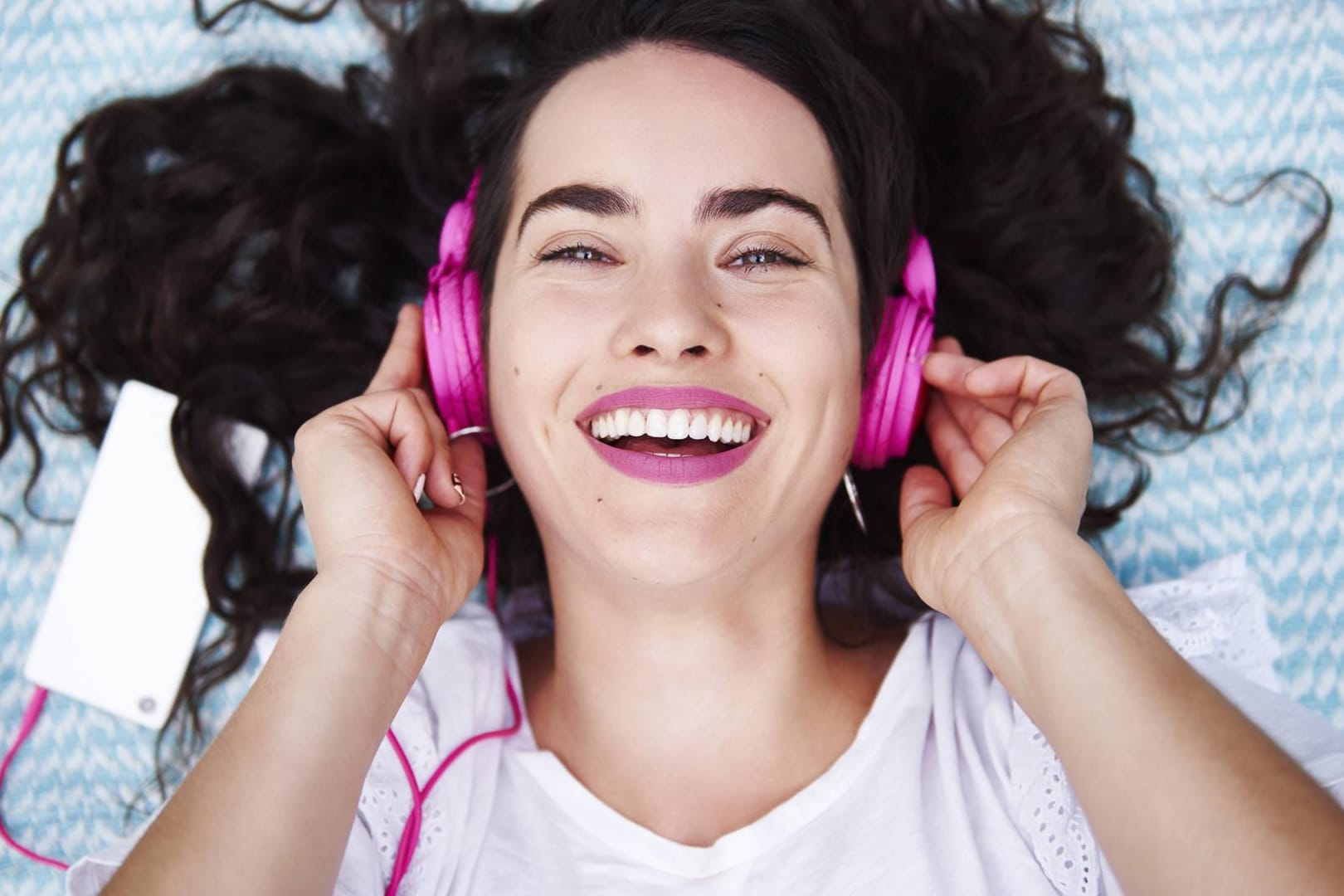 Eine junge Frau hört über pinke Kopfhörer Musik: Sogenannte "Zero Rating"-Tarife sind vor allem bei jungen Nutzern beliebt.