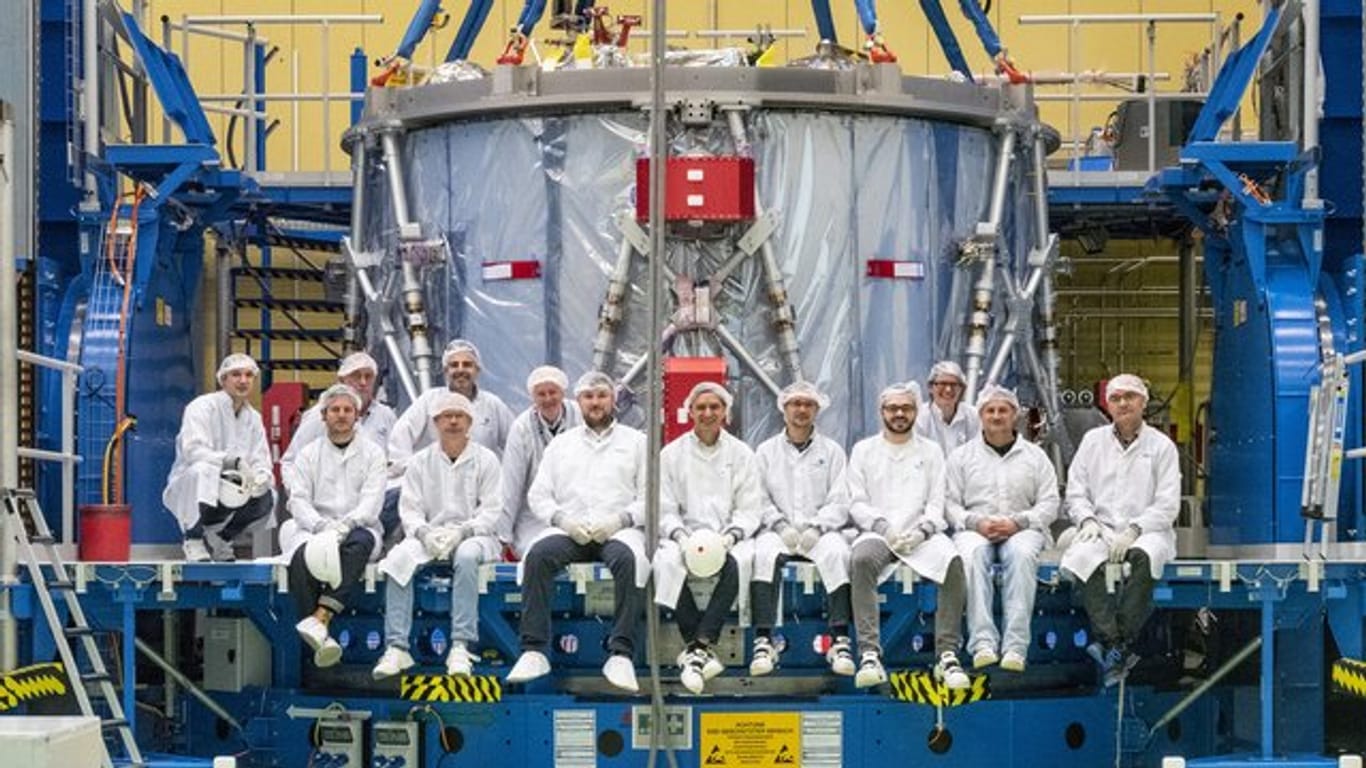 Ein Airbus-Team sitzt vor dem schon zum Teil verpackten Europäischen Servicemodul (ESM) für das US-Raumschiff "Orion".