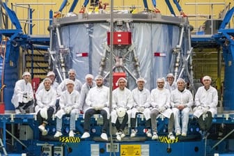 Ein Airbus-Team sitzt vor dem schon zum Teil verpackten Europäischen Servicemodul (ESM) für das US-Raumschiff "Orion".