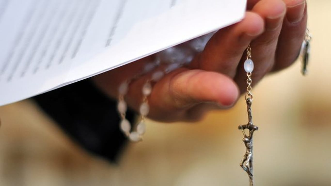 Rosenkranz und Schreiben in der Hand eines Priesters.