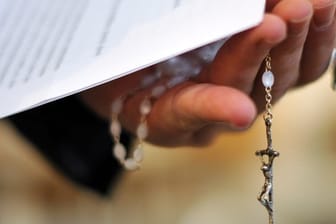 Rosenkranz und Schreiben in der Hand eines Priesters.