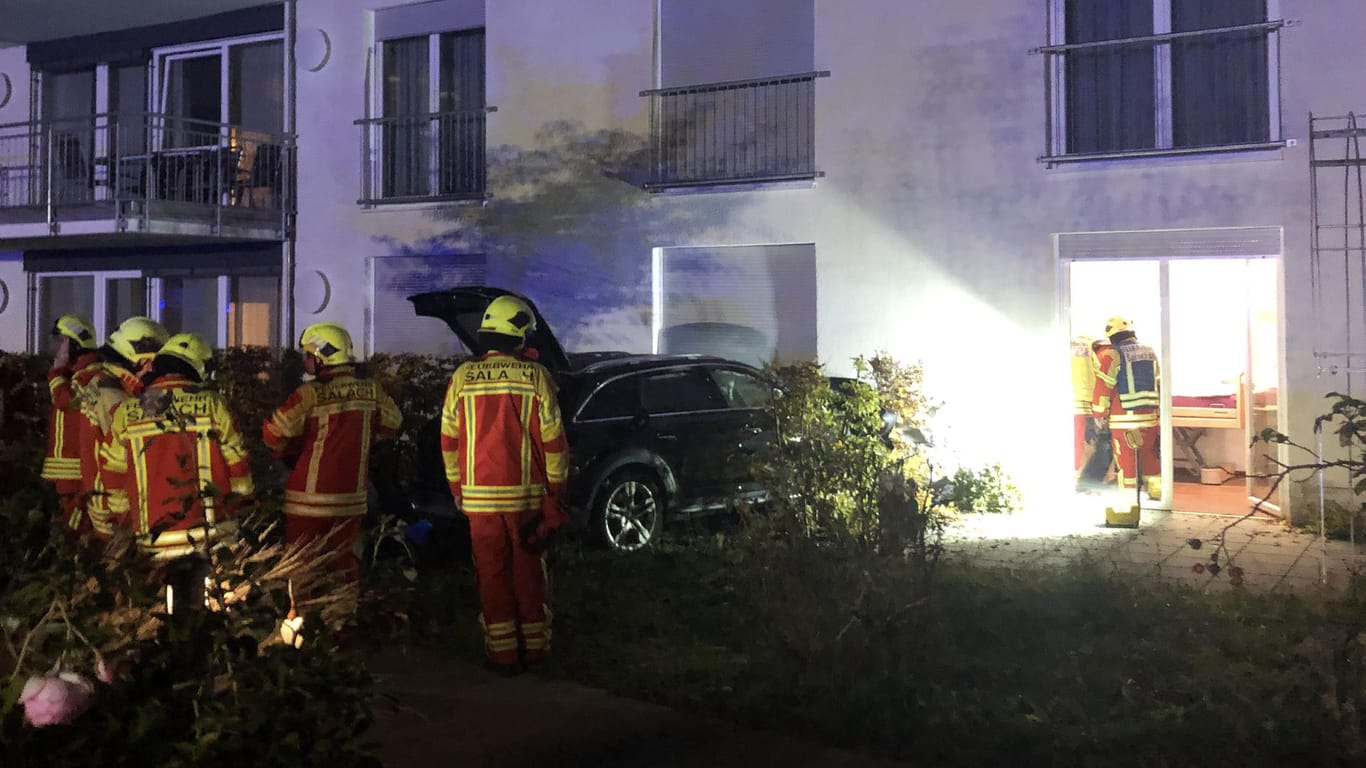 Einsatzkräfte der Feuerwehr stehen neben einem PKW am Seniorenheim: Auch der Autofahrer wurde leicht verletzt.