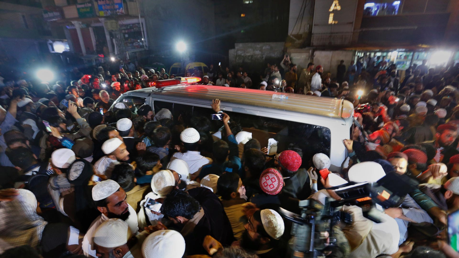 Menschen stehen neben einem Leichenwagen, in dem die Leiche des pakistanischen Geistlichen Maulana Samiul Haq transportiert wird: Die Hintergründe der Tat sind noch unklar.