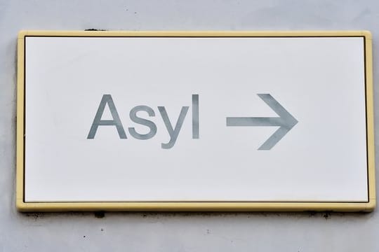 Ein Schild mit der Aufschrift "Asyl" hängt in einer Landeserstaufnahme für Asylbewerber (LEA) an einer Wand.