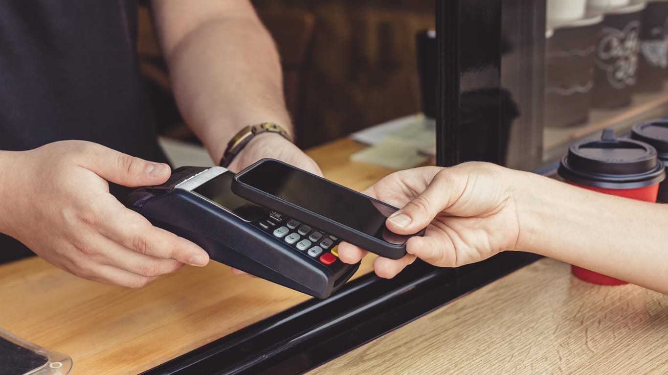 Eine Person bezahlt mit dem Smartphone: Mit Diensten wie Apple Pay können Smartphones die Kreditkarte ersetzen.
