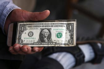 Ein iranischer Devisenwechsler hält eine US-Banknote: Seit August 2018 gelten wieder US-Sanktionen gegen den Iran, am Montag trat die zweite Runde an in Kraft.