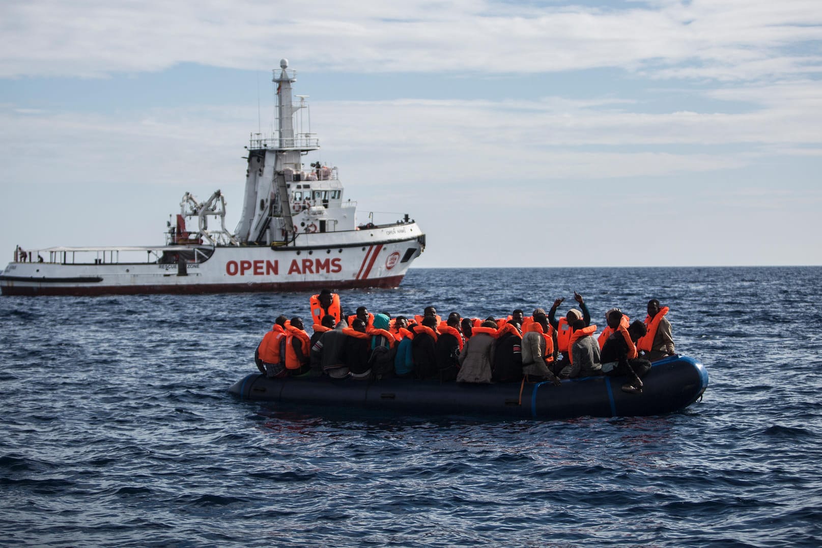 Flüchtlinge auf einem Schlauchboot freuen sich über die Ankunft eines Rettimgsschiffes: Mehr als 2.000 Menschen ertranken in diesem Jahr im Mittelmeer. (Archivbild)